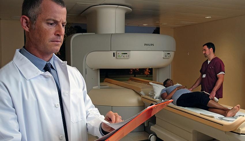 a doctor standing in front of a true open mri machine